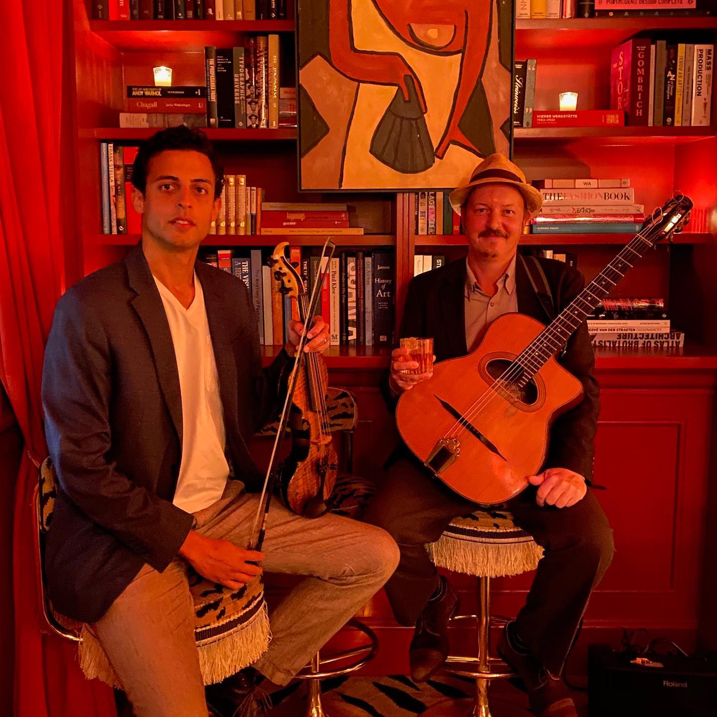 Photo of two musicians in a dimly lit, red bar.