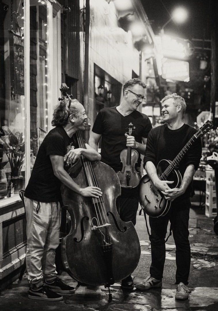 Black and white image of the three band members standing on the street.