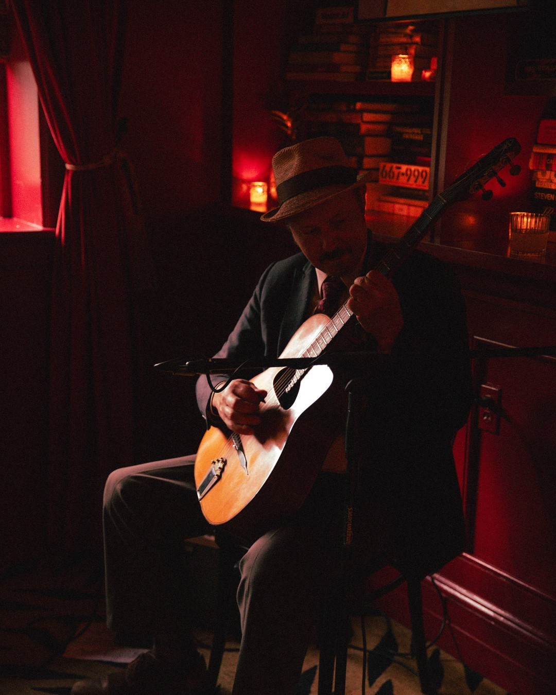 Musician playing guitgar in a dimly lit room by candlelight.